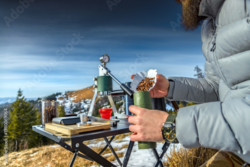 Manual portable espresso maker brewing coffee beans outdoors in mountains camping setup
