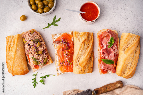 Variety of sandwiches with tuna, salmon y jamon or prosciutto for breakfast on white background, top view, Bruschetta snacks for wine.
