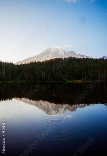 Calm Reflection Lake with mirror-like surface reflecting surrounding mountains and trees. Serene nature scene perfect for outdoor and landscape photography.