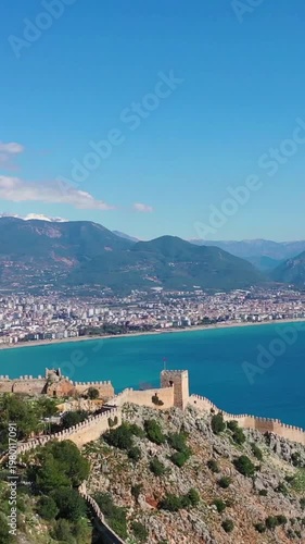 Aerial view of ancient stone walls of Alanya Fortress perched on a cliff above the Mediterranean Sea in Türkiye.