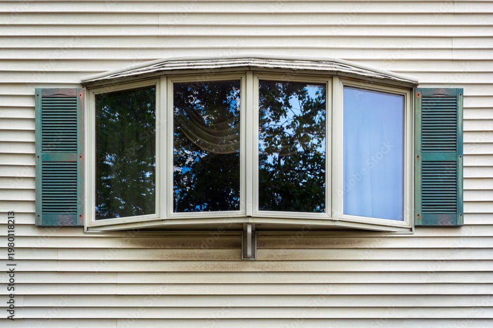 Fototapeta premium Classic bay window with green shutters on a light-colored vinyl siding house wall, Boston, Massachusetts 