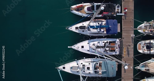 Overhead Marina Berths With Boats Lined Along Wooden Jetty, Varied Hulls And Masts Forming Geometric Pattern, Calm Green Water And Leisurely Atmosphere For Nautical