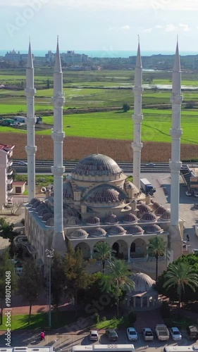 Aerial view of Manavgat Central Mosque in Türkiye, framed by dense residential buildings, showcasing grand Islamic architecture.	