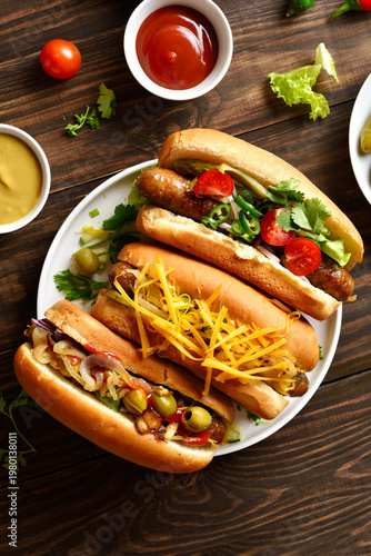 Hot dogs with different toppings on wooden table