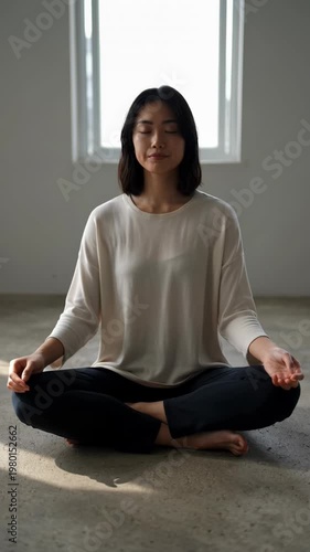 Woman meditates in a quiet room with natural light coming through windows during the afternoon