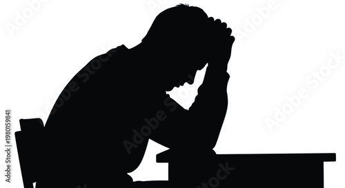Sad man sitting alone at a desk with his head in his hands feeling stressed