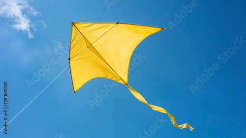 Yellow kite flying high in the clear blue sky. Simple, bright, and minimalist summer concept.