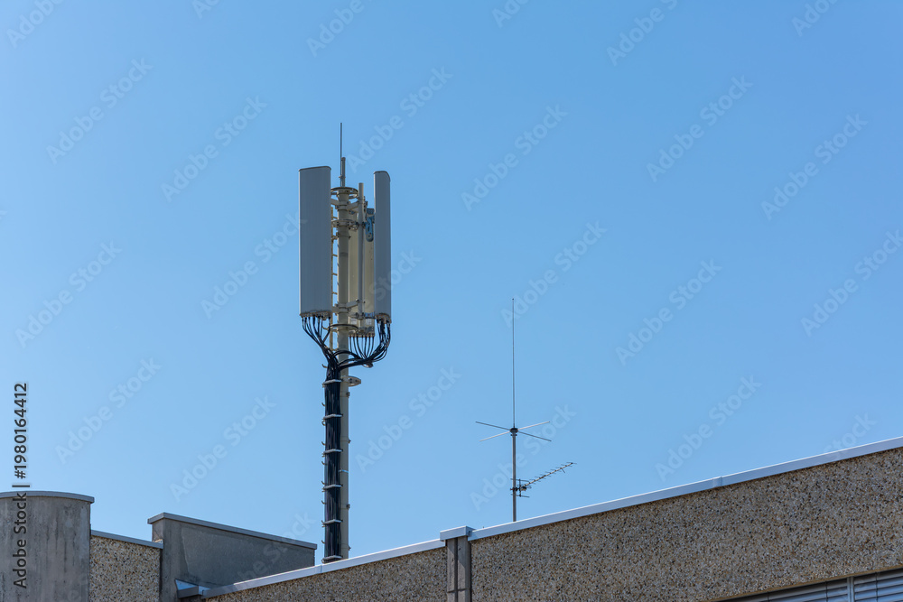 Obraz premium Cellular Antenna on Rooftop Against Blue Sky