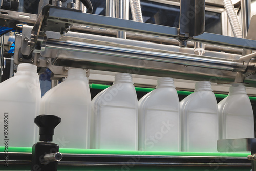 Φωτογραφία Plastic jugs move along green conveyor belt in factory