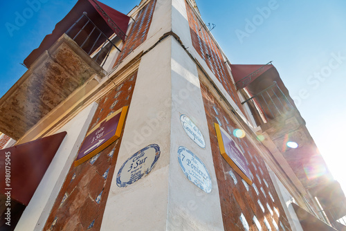 Sunny street corner with traditional Talavera tile signs indicating Calle 3 Sur and 7 Poniente on brick building facade with dramatic lens flares in Puebla, Mexico