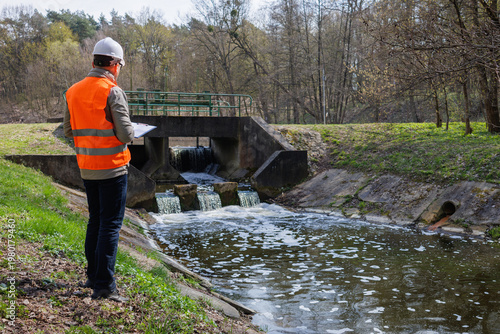 Photography Environmental engineer inspecting a river dam and water level control system for ecological monitoring