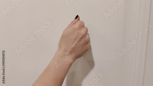 Close-up of a hand knocking on a door. Everyday communication, arrival and visitor concept, home or office entrance. Simple gesture symbolizing greeting, request, access and opportunity.