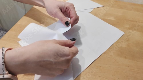 Close-up of hands tearing paper by hand. Concept of destruction, rejection, recycling, document disposal, creativity or stress relief. Simple manual action with paper on a clean background.