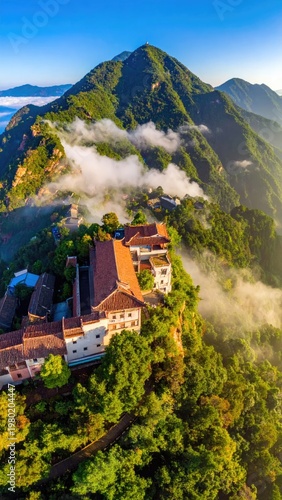 A picturesque village nestles amidst lush green mountains shrouded in ethereal morning mist.