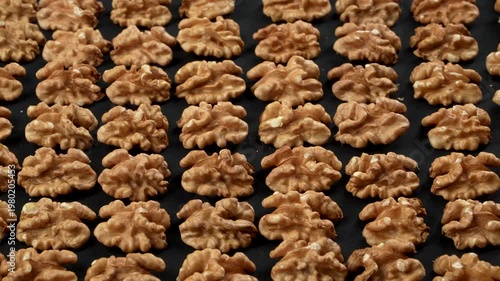 Densely packed infinite pattern of whole organic walnuts in shell. Shadowless harmonious soft lighting highlights the complex rugged texture. Premium conceptual background.