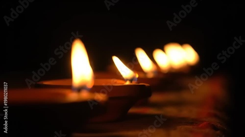 Row of lit diyas creating a warm and inviting ambiance in darkness.