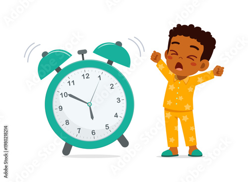 Sleepy Black boy yawning and stretching in yellow star pajamas waking up from loud ringing alarm clock
