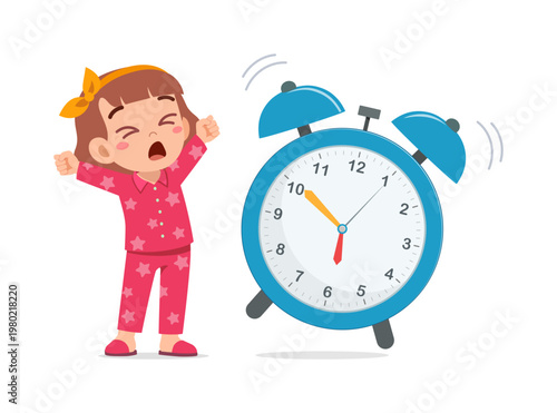 Cute young girl yawning and stretching next to a loud ringing alarm clock in the morning