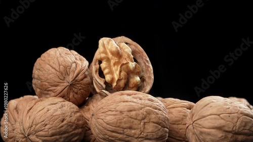 Neatly arranged shelled walnut kernels rotating in a geometric pattern on a black background. Premium macro organic food concept.