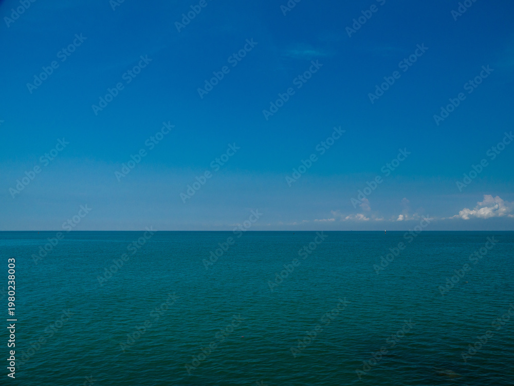 Obraz premium Serene tropical beach with crystal clear turquoise water, gentle waves, and a bright blue sky with fluffy white clouds. peaceful and relaxing summer scene perfect for panorama and travel concepts.