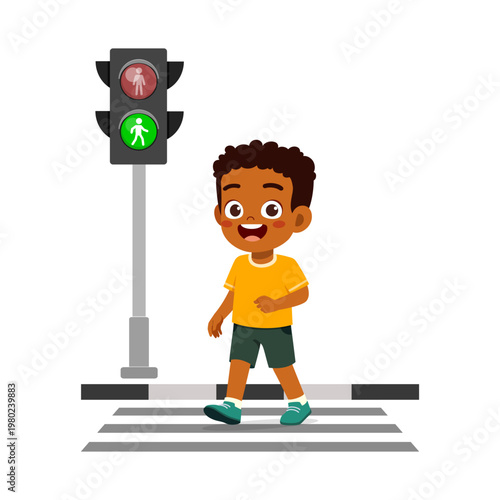 Happy African American boy walking safely on crosswalk with green pedestrian traffic light on