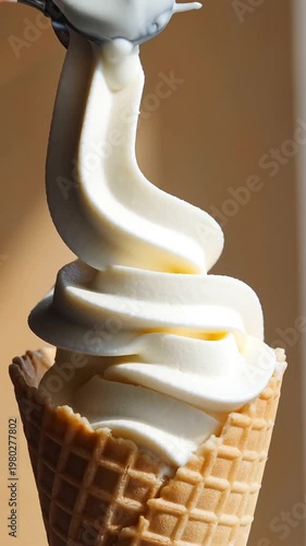 Creamy vanilla soft serve ice cream swirling into waffle cone