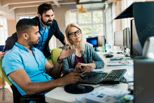 Coworkers collaborating on project at modern office