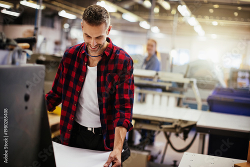 Tableau sur toile Smiling print shop worker operating industrial machine