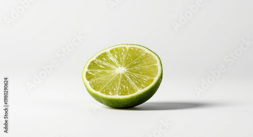 Cut lime slice positioned on an even white background