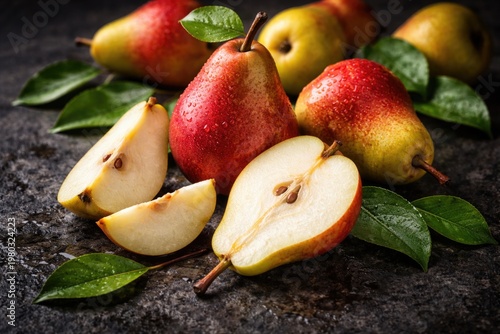 Fresh ripe pears with juicy slices and vibrant green leaves on a dark textured stone surface