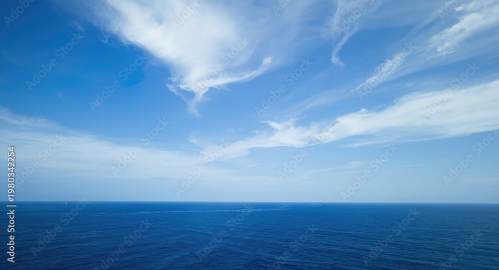 Fototapeta premium Wide open sky filled with drifting clouds and deep blue sea