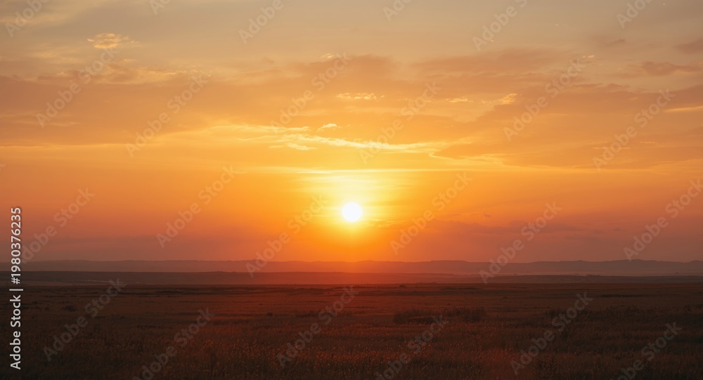 Fototapeta premium Sunset splashing warm golden colors across a large open area with light cloud patterns in summer
