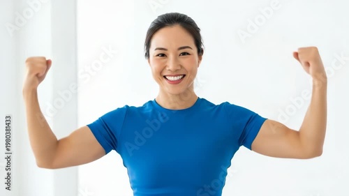 Happy Asian Woman Flexing Muscles Demonstrating Strength and Fitness.