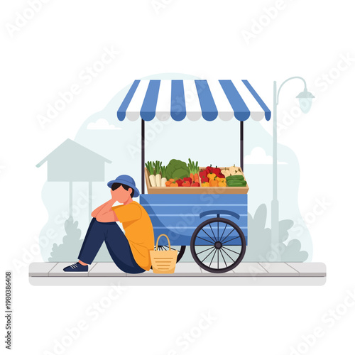 A male street vendor sitting on the sidewalk next to a mobile vegetable cart with a blue and white striped awning, looking tired or discouraged while selling various fresh produce.