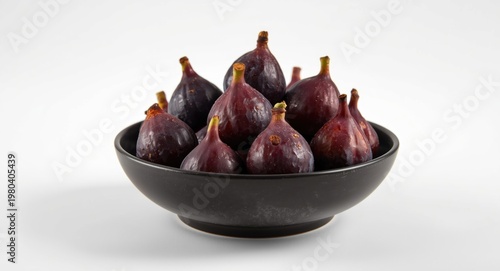 Purple figs arranged carefully in a smooth black bowl resting on a white background