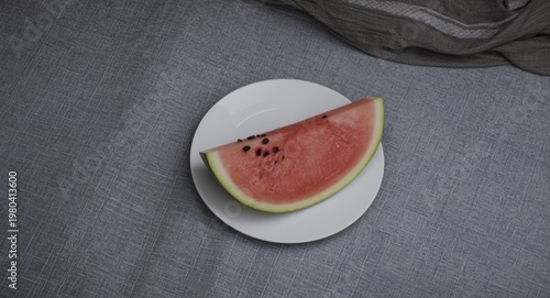 Watermelon slice on white plate with gray tablecloth backdrop