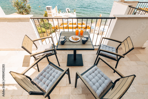 Fotografie Sunlight bathes cozy balcony with comfortable chairs and scenic sea horizon view