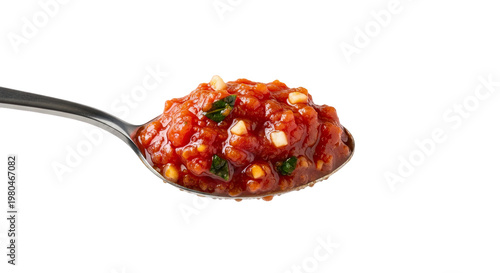 A spoonful of chunky red sauce with herbs and garlic pieces, showing its thick, vibrant, savory texture.