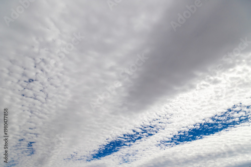 Altocumulus clouds create a textured, layered sky with bands of white and blu...