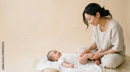 A mother is smiling while playing with her baby on a soft rug in a bright room