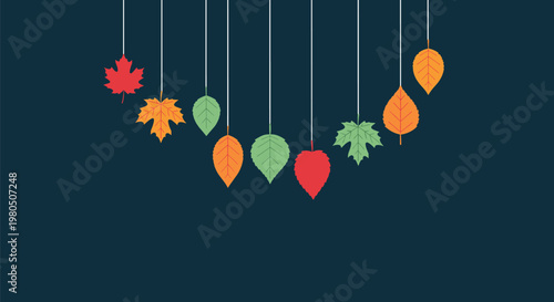 Vibrant autumn leaves in shades of orange and green hang from strings against a dark blue background to create a seasonal fall decoration.