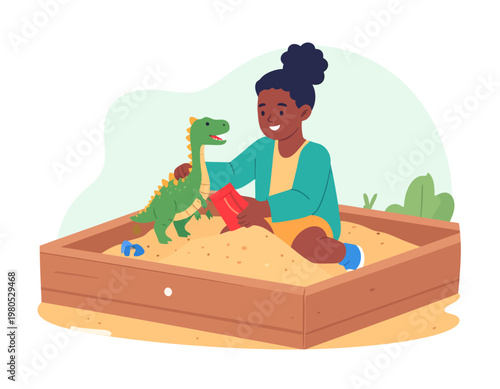 A young girl with dark skin and hair is happily playing in a sandbox with a green toy dinosaur and a red shovel.