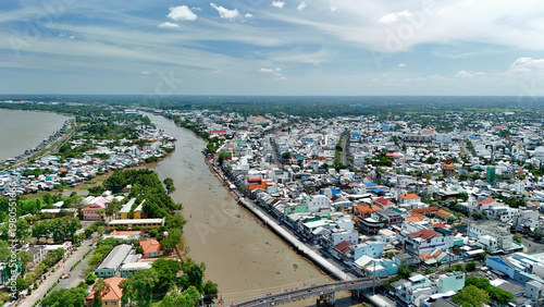 Quadro su tela Sa Dec City, Dong Thap Province, Southwest Vietnam – 4K aerial drone view of Mekong Delta riverside cityscape with bridges, riverfront houses, canals, urban skyline, fruit orchards and rice fields
