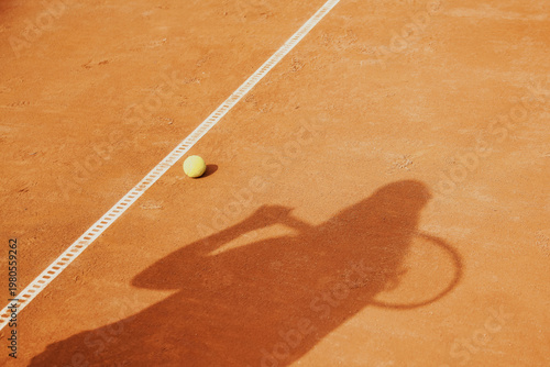 Fotografie On a clay tennis court, a yellow ball sits next to a white line