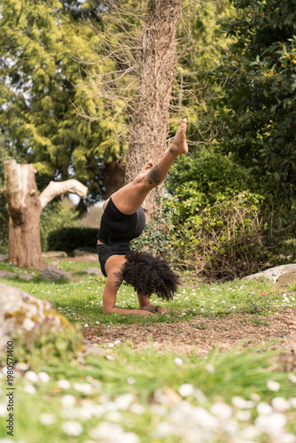 Woman practicing yoga forearm stand in nature