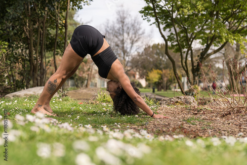 Woman practicing downward facing dog yoga pose outdoors