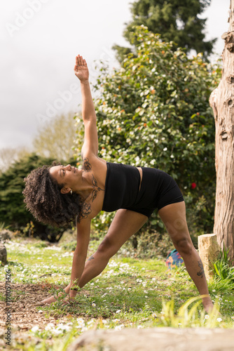 Woman practicing triangle pose yoga outdoor in nature