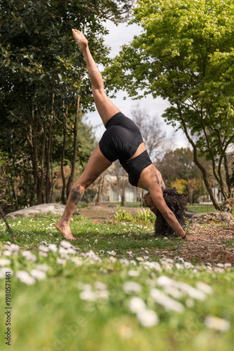 Woman practicing three-legged downward dog yoga pose outdoors