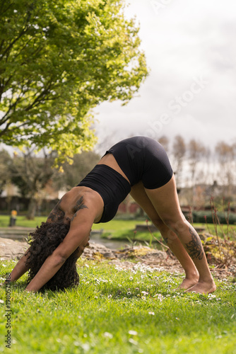 Woman practicing downward-facing dog yoga pose outdoors
