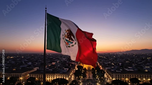 Bandera de México ondeando al atardecer sobre la Catedral de Guadalajara, vista aérea cinematográfica del centro histórico para turismo, patriotismo y festejos del Cinco de Mayo.